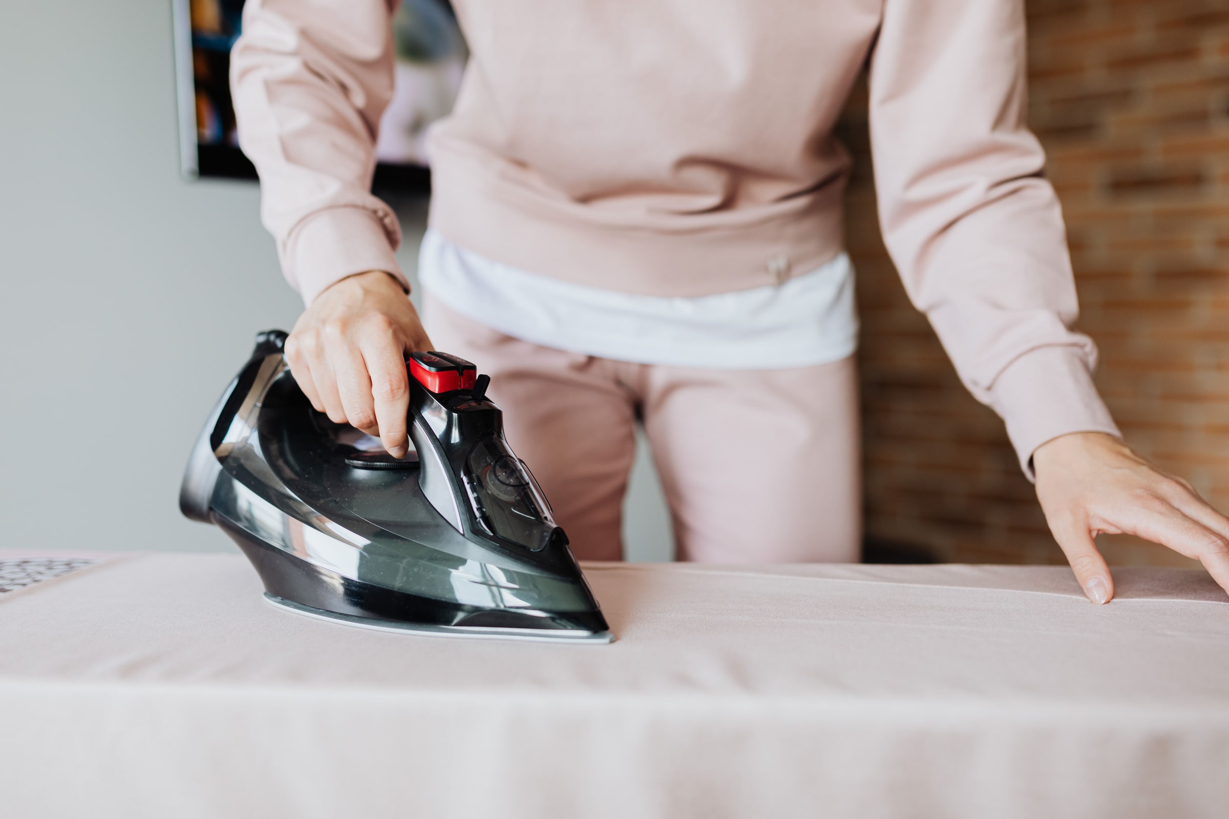 Hands pressing a garment with a steam iron